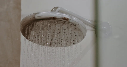 Water running from a chrome shower head while the surrounding connections remain visible for leak inspection.