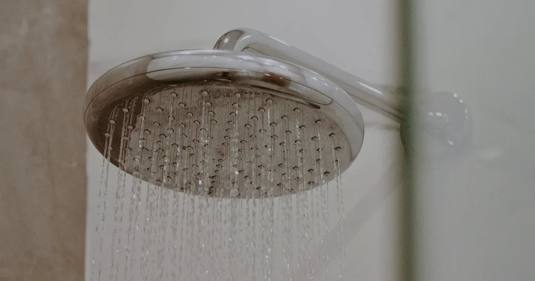 Close-up of a chrome shower head in a tiled bathroom, representing routine shower filter maintenance.