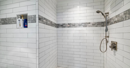Bright modern shower with white tile and chrome fixtures, representing the point where a shower filter treats water.
